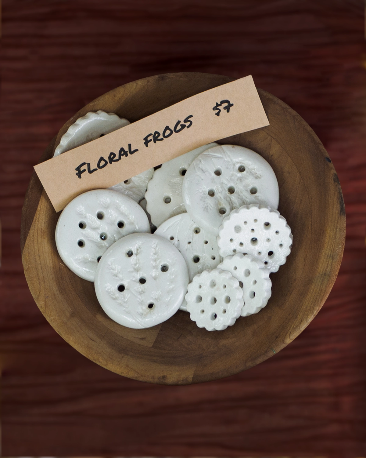 Handmade ceramic floral frogs in a wooden bowl